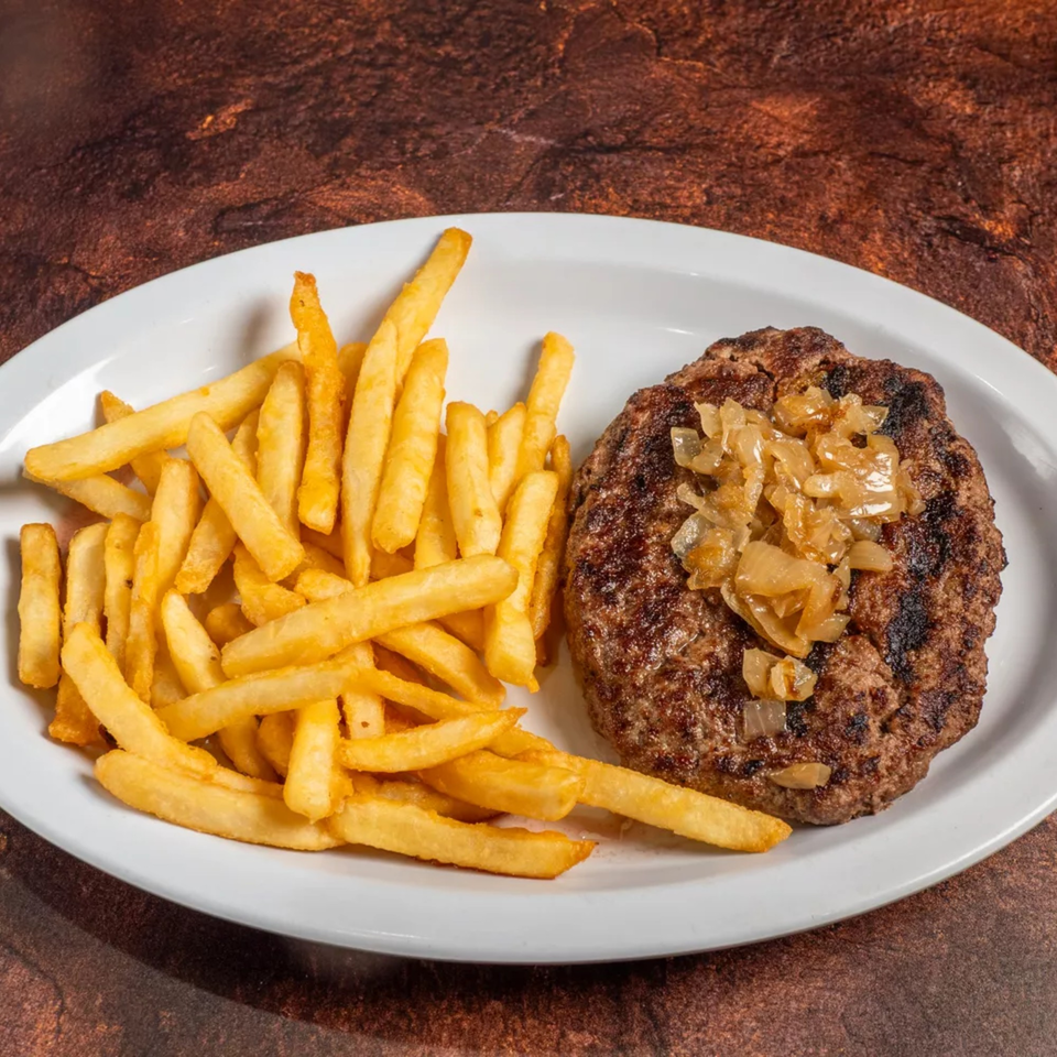 Grilled hamburger patty topped with caramelized onions, served with a side of golden french fries.