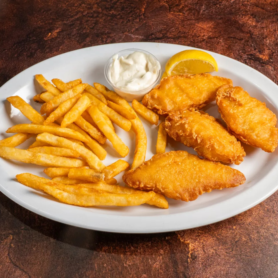 Golden-brown fish and chips with a side of tartar sauce and a lemon wedge on a white plate.